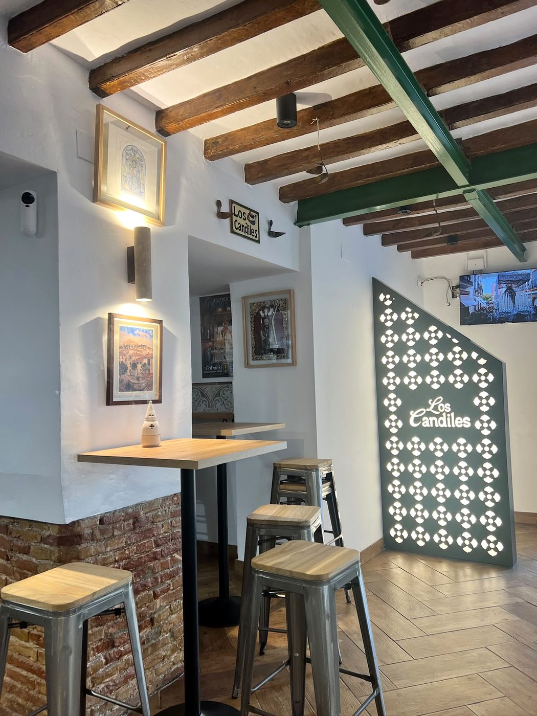 Interior de la taberna con mesas altas y la celosía con el logo