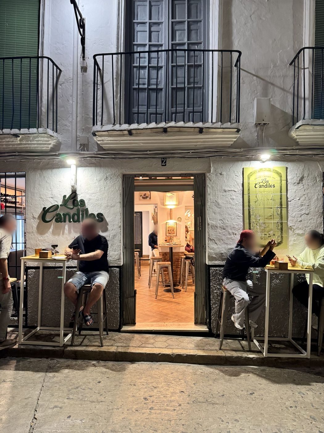 Clientes en la puerta de Los Candiles, con el rótulo en la fachada